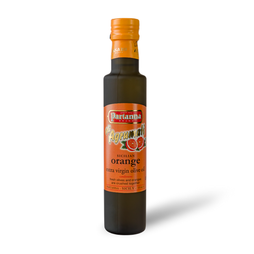 A dark glass bottle of Partanna Sicilian Orange Extra Virgin Olive Oil with a bright orange cap and a label that showcases the product name and orange imagery.