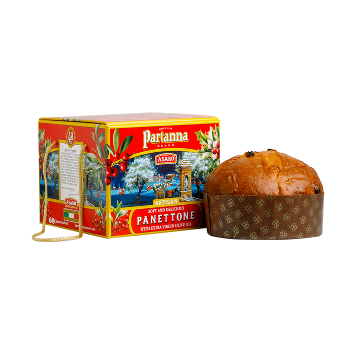 A box of Partanna Artisan Panettone with a red and gold design, next to a round panettone cake wrapped in brown paper. The box features a scenic image and text highlighting the artisan quality of the product